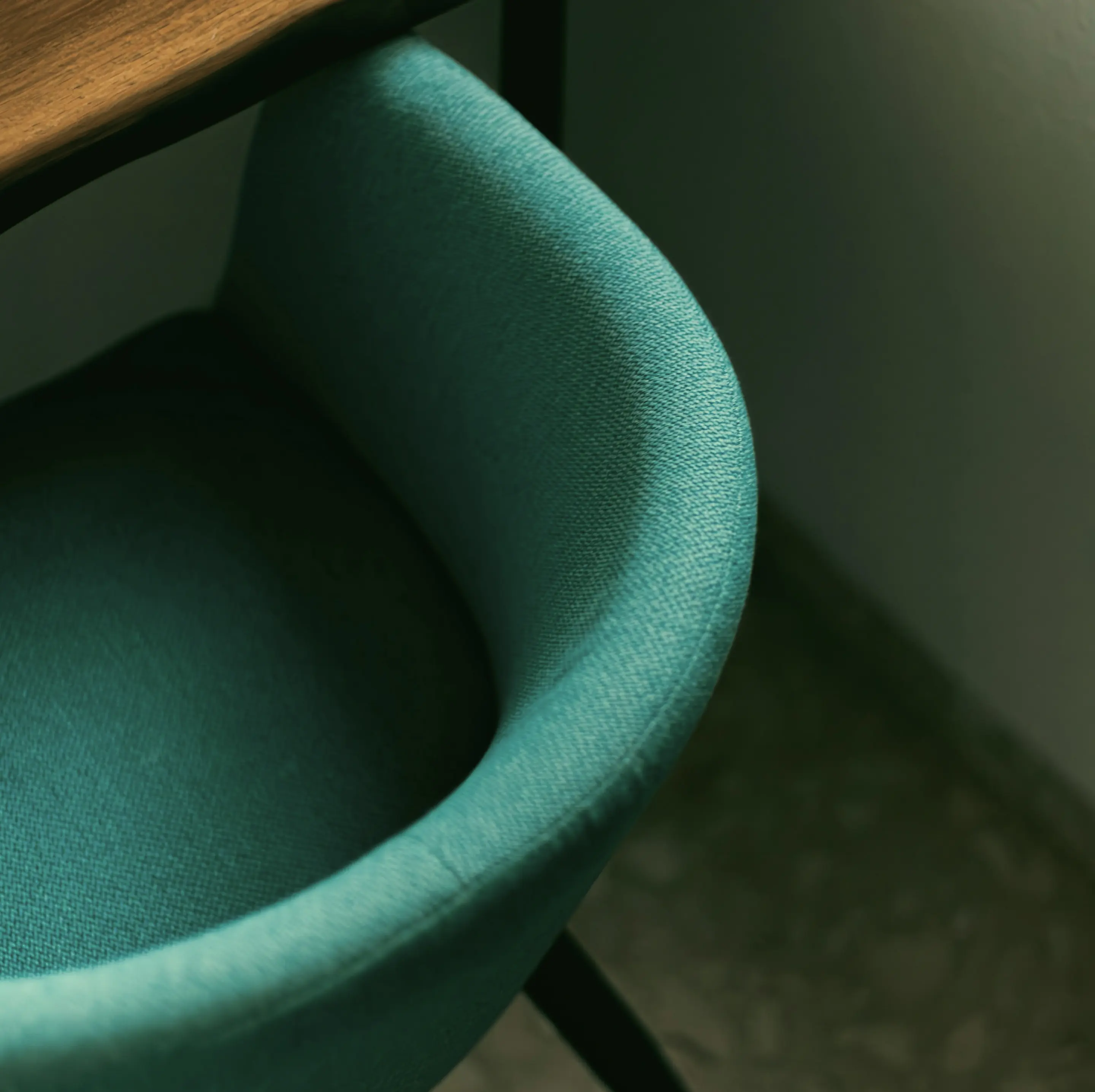 Close view of green woven upholstery and a wooden tabletop